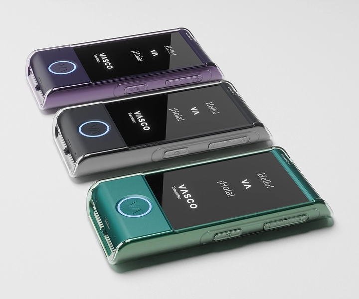 Three Vasco Translator M4 devices lying on a table in transparent silicone cases in three different colors, with screens turned on showing the Vasco logo and illuminated LED buttons.
